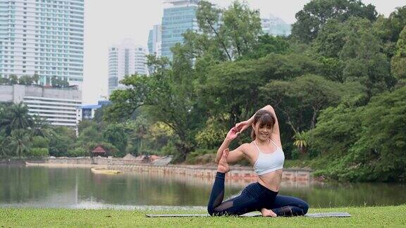 美丽的年轻亚洲女子练习瑜伽码头在公众湖公园