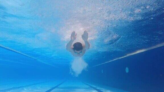 水下低角度看亚洲华人男子游泳蝶泳风格在游泳池