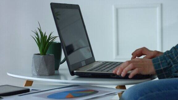 女性在家庭办公室用笔记本电脑键盘打字