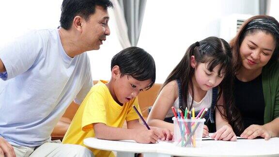 亚洲父亲和母亲看着孩子在家里画画