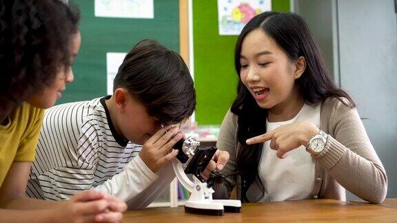 亚洲学校老师帮助学生使用显微镜