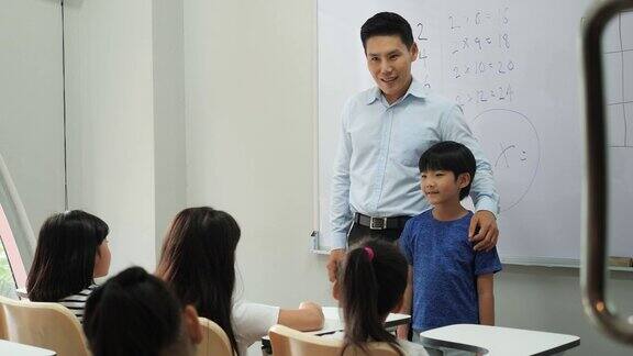 一位亚洲老师在学校介绍班上的新学生小男孩和小女孩一起交了新朋友理念教育礼仪之邦
