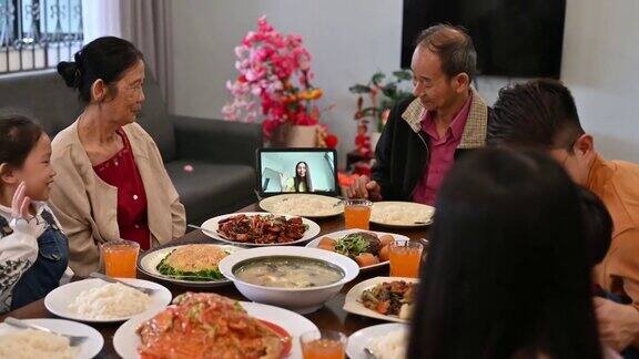 快乐的亚洲家庭在线上过年在家里用数码平板电脑视频电话和亲戚们团聚吃团圆饭