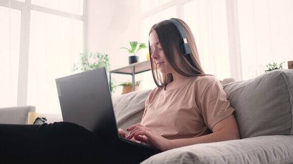 快乐的女人在家听音乐用笔记本电脑工作
