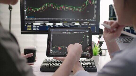 两个女商人使用数字平板电脑分析股票市场数据图