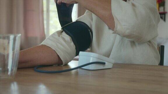 一位老年妇女正在家中用数字压力表测量自己的血压和心率
