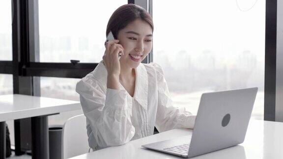 年轻快乐漂亮的亚洲女员工在手机上谈笑风生