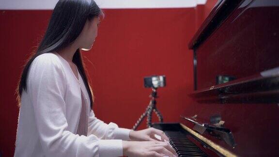 亚洲妇女学习弹钢琴在线学习与教师与数字平板电脑