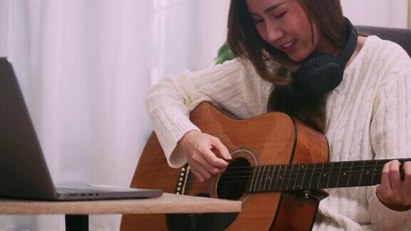 年轻的女艺术家在家学习原声吉他