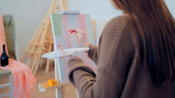 年轻的艺术家在工作室工作写静物女孩在画布上画一幅画
