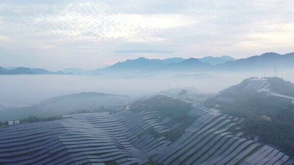 在晨雾中鸟瞰起伏山坡上的太阳能发电厂