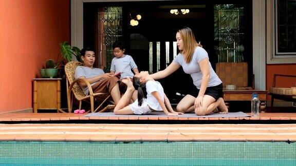 妈妈和她的女儿在家里游泳池附近做伸展运动
