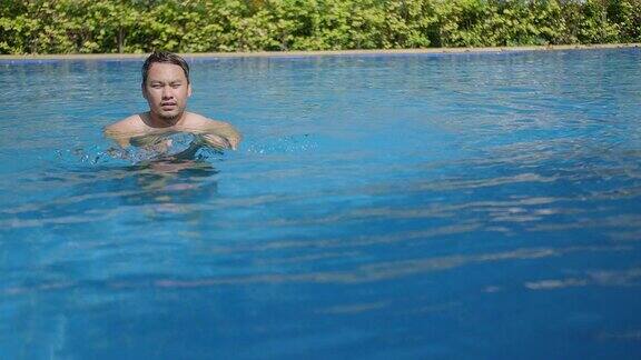 亚洲男子在夏日阳光灿烂的日子里在游泳池里放松