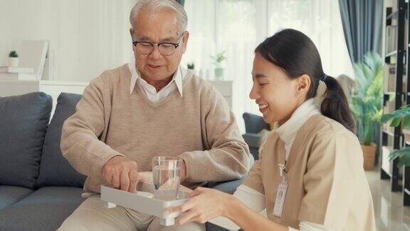 年轻亚裔女性护理员护理员赡养老年人家中老年病人饮水后服药治愈或治疗老年人退休后的疾病帮助赡养