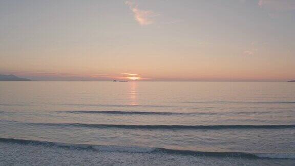 日落时海浪向海岸移动的无人机