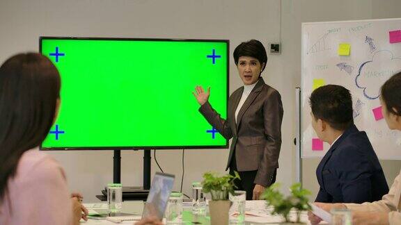 业务演示迷人的女商人在绿色屏幕前向她在会议室的同事做报告
