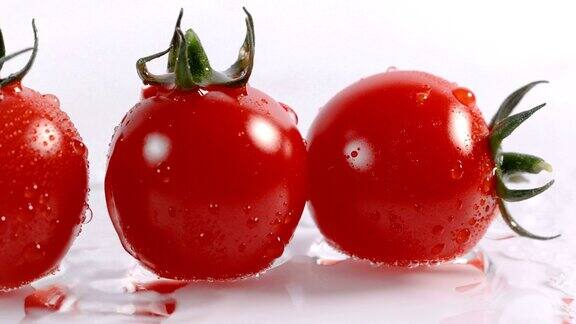 水滴落在白色背景上的新鲜的红色西红柿上