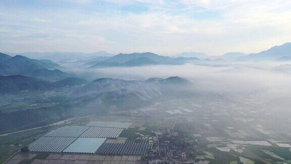 在晨雾中鸟瞰有机农场和山顶太阳能发电站