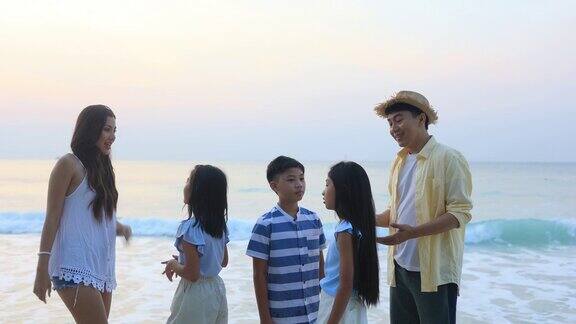 快乐的亚洲父母带着3个孩子享受早晨的海滩散步-日出中的家庭乐趣
