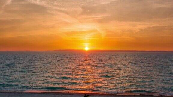 一对夫妇坐在海滩上看日落温暖而浪漫