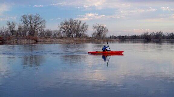 一名男子在平静的湖面上划着皮划艇