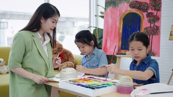在一所艺术学校一位美丽的亚洲老师正在给孩子们上绘画课这是教育