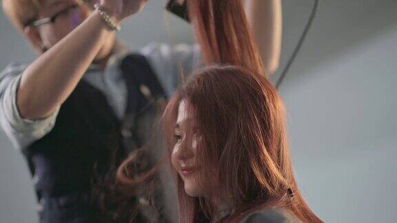 发廊亚洲华人女性发型师在发廊为她的顾客吹梳湿长发