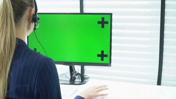 在办公室使用绿屏笔记本电脑的女性