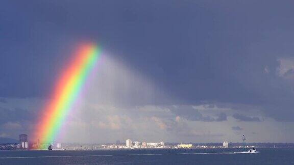 小船向城市驶去暴风雨中出现了戏剧性的彩虹景观