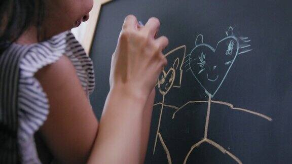 在家里客厅的黑板上快乐的母亲正在教女儿用彩色粉笔画画