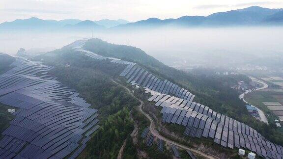 无人机在晨雾中观察山顶上的太阳能发电厂