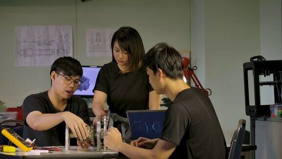 年轻的亚洲机械工程师团队在汽车工业设计头脑风暴关于原型发动机在工作室车间技术与创新理念