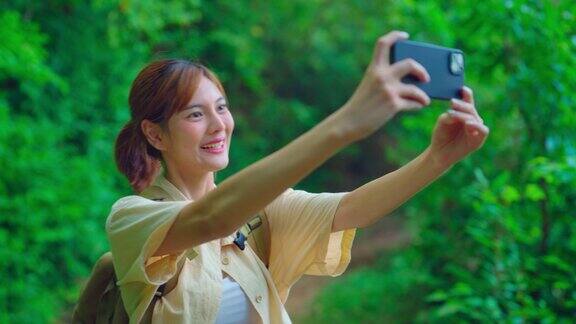年轻的亚洲旅行者在森林里散步时用手机拍照