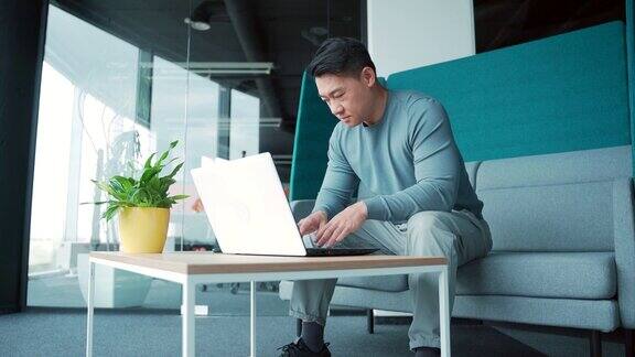 亚洲男性自由职业者在现代办公室的笔记本电脑上工作办公中心的男学生或老师在电脑上打字聪明的专业员工有创造力