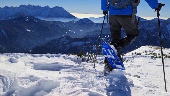 一个背着背包的活跃男子在奥地利卡林西亚卡拉万克斯雪山的山峰上欣赏风景雪鞋朱利安阿尔卑斯山阳光灿烂的冬日慢动作