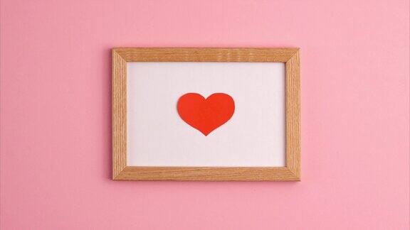 定格动画红纸心木框架在粉红色的背景在中心边情人节母亲节爱情关系浪漫的纪念日婚礼节日概念平躺