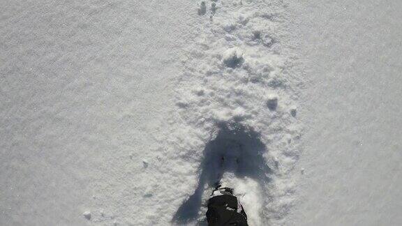 在刚下的雪中穿雪鞋山路POV徒步旅行者的观点靠近雪鞋踩在新雪上