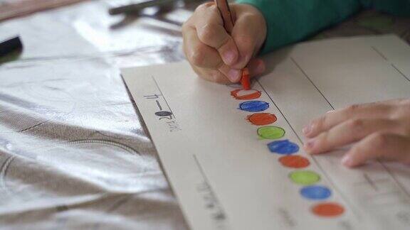 近距离观看一个孩子用蜡笔在纸上画画或在家里做作业
