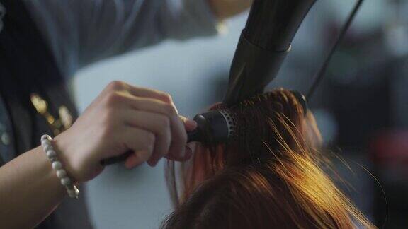 亚洲华人女性发型师吹梳湿长发为她的客户在发廊