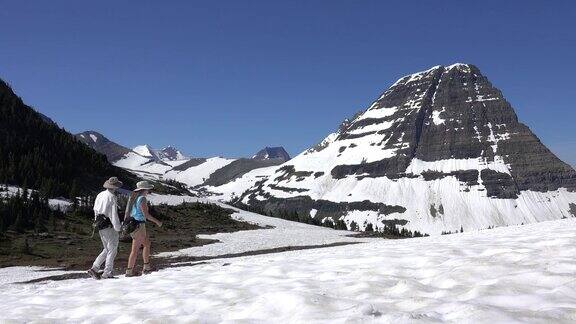 男人女人夫妇徒步旅行冰川国家公园洛根山口雪原熊帽子山蒙大拿州