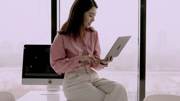 美丽的亚洲白领女性在办公室里用笔记本工作