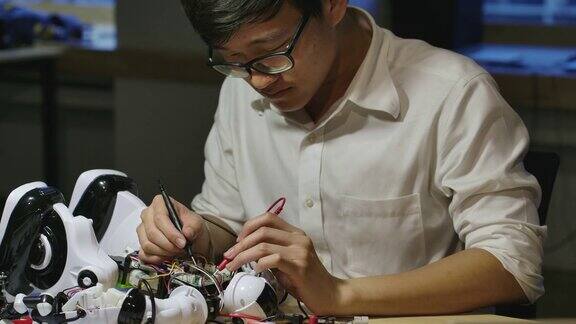 年轻的亚洲电子开发工程师晚上在计算机科学研究实验室里建造、测试、修理机器人有技术或创新观念的人