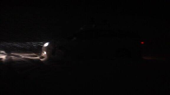 冬天驾驶雪在晚上在深雪风暴-汽车的前灯做一个转弯和开车离开