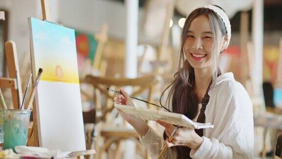 美丽的亚洲女艺术家微笑看着相机在艺术工作室肖像