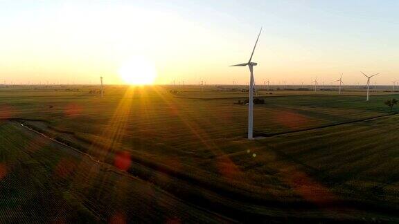 空中乡村田野和风力涡轮机到日落与光束
