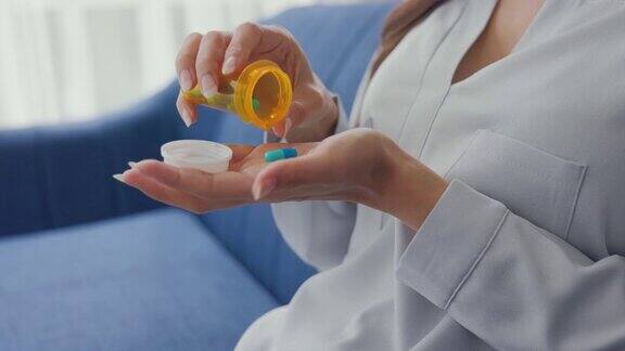 一个女人的手从药瓶里倒出许多药片