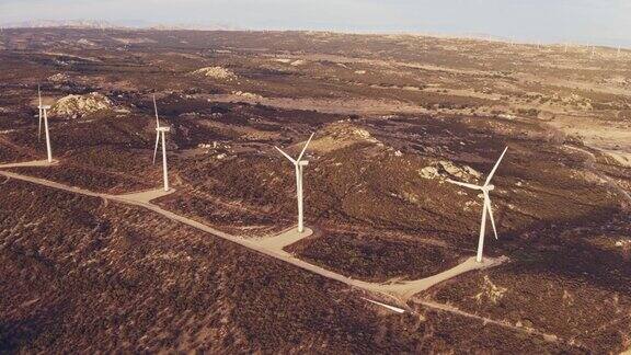 鸟瞰图风力涡轮机创造清洁的可再生能源在山区景观日落