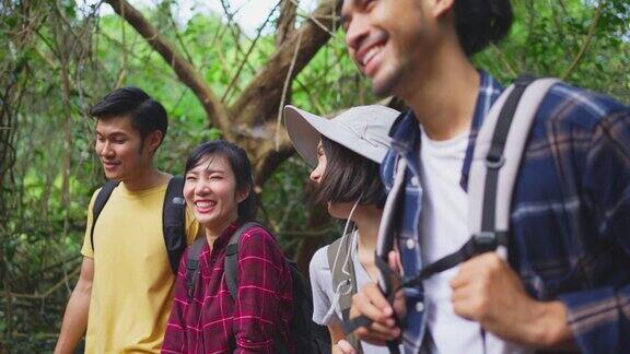 一群年轻的亚洲男人和女人朋友一起在森林里旅行他们在大自然中感到清新和放松看着并指向风景然后继续散步快乐和乐趣