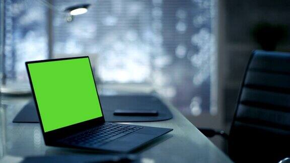 现代极简主义办公室的桌子上放着一台带有绿色屏幕的笔记本电脑