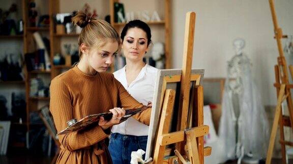 有经验的美术老师与漂亮的女孩有天赋的学生在充满艺术品的工作室里画画和交谈分享经验
